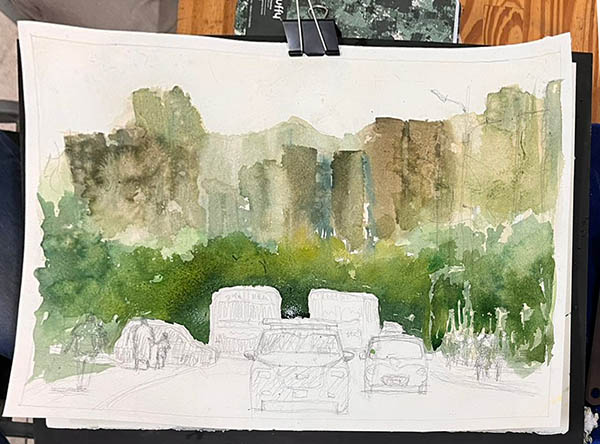 Pintura en acuarela que muestra un paisaje urbano con árboles verdes en primer plano y edificios de color marrón y verde al fondo, además de coches en una carretera.